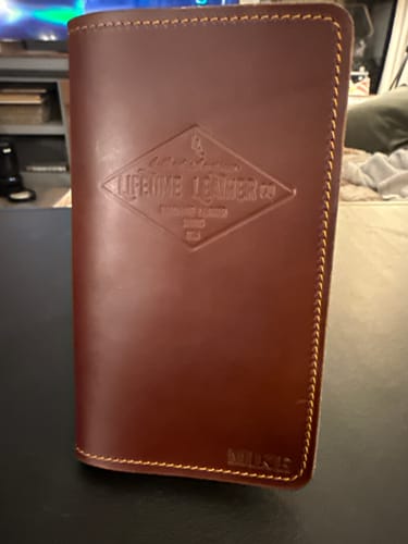 Customer's personalized brown leather Field Notes Wallet standing upright, showing the embossed logo and 'MIKE' on the front.