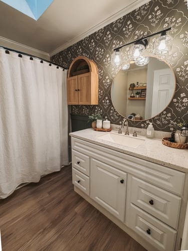Customer's bathroom featuring the Della Wallpaper with a white floral pattern on a dark wall above the vanity.