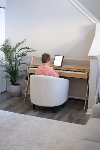 Ein Kind des Rezensenten sitzt am hellen Donner OURA™ R300 Digitalpiano im Wohnzimmer.