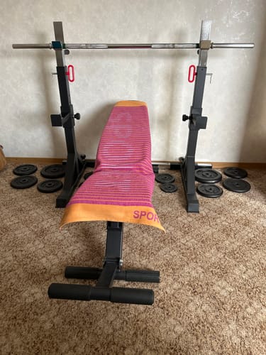 Kunde zeigt das schwarze Free Stands Squat Rack, das für das Bankdrücken mit einer Hantelbank aufgebaut ist.