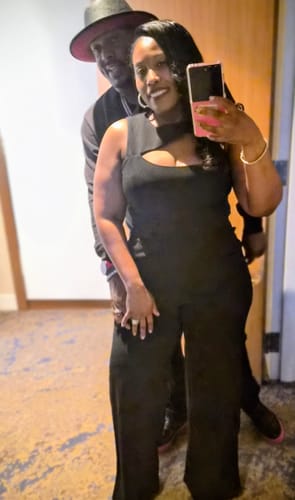 Reviewer takes a mirror selfie wearing the black Phase Jumpsuit, showing the asymmetrical cutout.