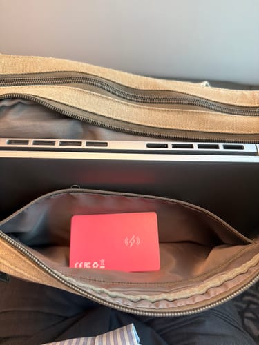 Customer's pink SPOTMINDERS Tracking Card placed discreetly inside an open pocket of a canvas bag.