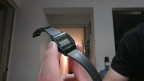 Un cliente sostiene en la mano su reloj Casio Vintage F-84W-1 negro, mostrando su perfil.
