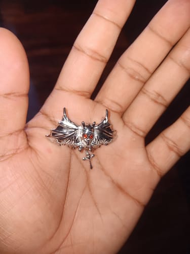 Customer holding the silver DAISY THE DAYSTALKER PENDANT in their palm, showing the detailed bat shape and red eyes.