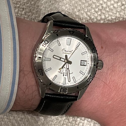 Cliente usando el elegante reloj Orient Mako 40 Peanuts en la muñeca, junto al puño de una camisa.