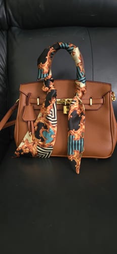 Reviewer's brown, structured Warkin Bag with a decorative scarf on the handle, resting on a black leather surface.