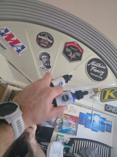 Customer's hand holding two dropper bottles of Meraki Blu Methylene Blue in a room with stickers in the background.