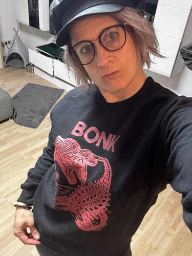 Reviewer wearing the black Late Cretaceous Bonk Crewneck, showing the large pink dinosaur graphic.