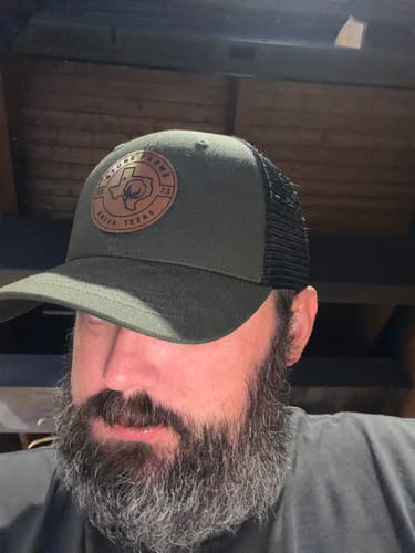 Customer wearing the dark green Big Trucker Hat with a black mesh back, pulled down low.
