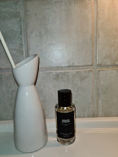 Customer's bottle of Rouge Avenue Eau de Parfum resting on a white bathroom counter against a tiled wall.