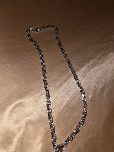 Customer's 6MM MINI ARIES CHAIN with interlocking links laid out on a silky tan surface.