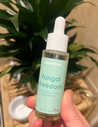 Reviewer holding the clear glass bottle of Fungal Freedom nail treatment oil.