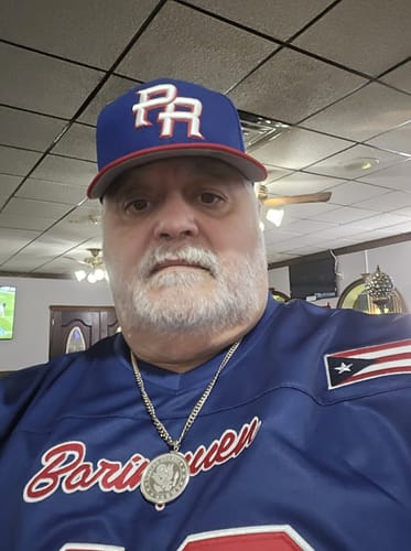 Customer wearing the blue Puerto Rico Heritage Football Jersey with 'Borinquen' script and a flag patch on the sleeve.