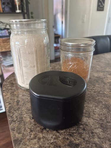 Customer's black Mason Genie® Vacuum Sealer Kit on a counter next to two filled glass mason jars.