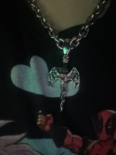 Close-up of a customer wearing a silver-colored chain necklace with an ornate, axe-shaped pendant.