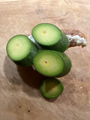 Ein Kunde zeigt aufgeschnittene, kernlose Avocado Cocktails auf einem Holzbrett.