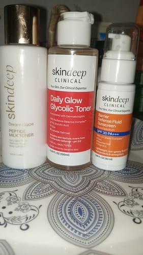 Customer's Dream Glaze Peptide Milk Toner shown with a Skindeep toner and sunscreen on a patterned surface.