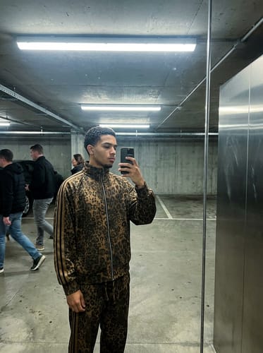 Reviewer wearing the full cheetah print tracksuit in a mirror selfie in a parking garage.