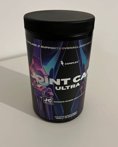 A customer's black tub of Joint Care Ultra supplement with a colorful, graphic label, shown on a plain surface.