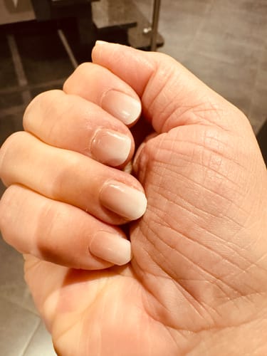 Nahaufnahme der Hand einer Kundin, die die Babyboomer Nude UV Gel Wraps auf kurzen, gepflegten Nägeln zeigt.