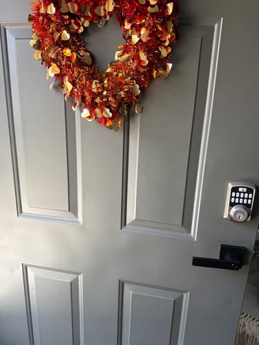 Customer's installed gray door with a black handle, keypad lock, and a decorative wreath.