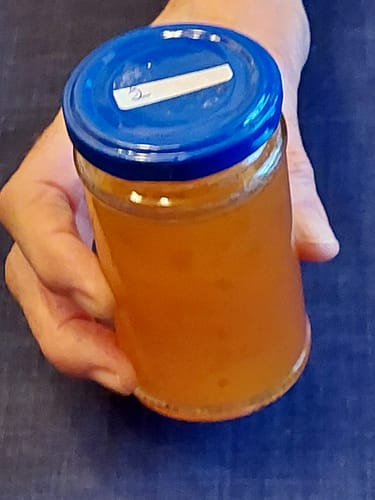 Ein Kunde hält ein Glas mit selbstgemachter Marmelade aus den Bitterorangen in der Hand.