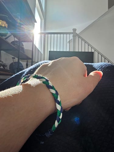 Reviewer showing the woven DAVID Bracelet in blue, green, and white on their wrist.