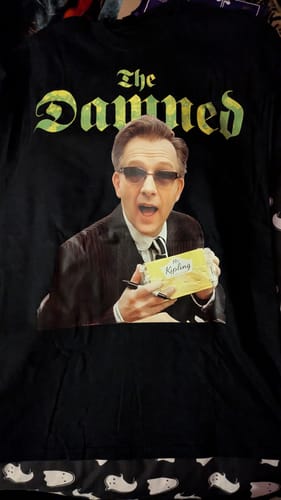 Customer's black unisex t-shirt showing a fun graphic of 'The Damned' and a man holding a package of cakes.