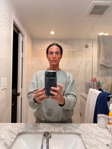 Reviewer showing their healthy, glowing skin in a mirror selfie after using The Micro Infusion System.