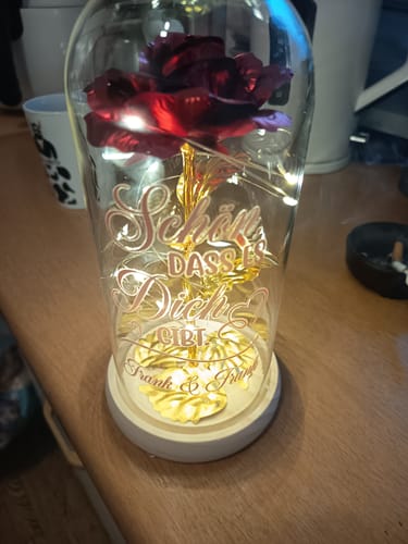 Kunde zeigt die personalisierte Rose in einer beleuchteten Glaskuppel mit Gravur.