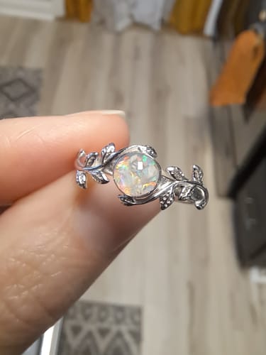 Close-up of a reviewer holding the Leaf Opal Cremation Ring, showing its silver leaf band and iridescent opal stone.