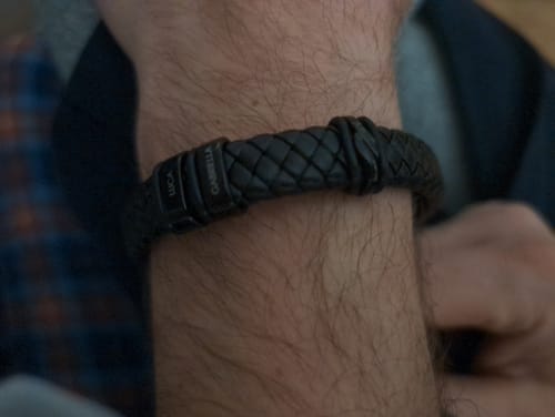 Close-up of a customer wearing the black braided bracelet with personalized pendants showing the names 'Luca' and 'Gabriella'.