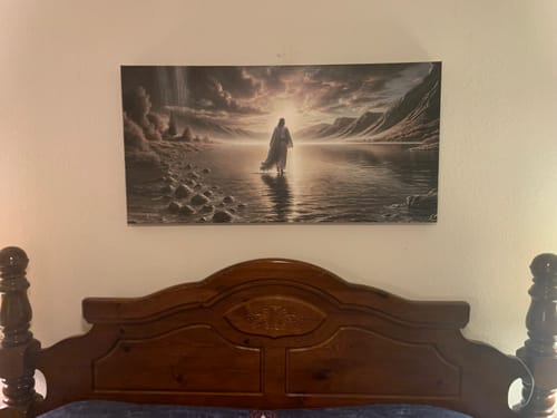 Customer's Walking on Water wall art hanging on a bedroom wall above a dark wooden headboard.
