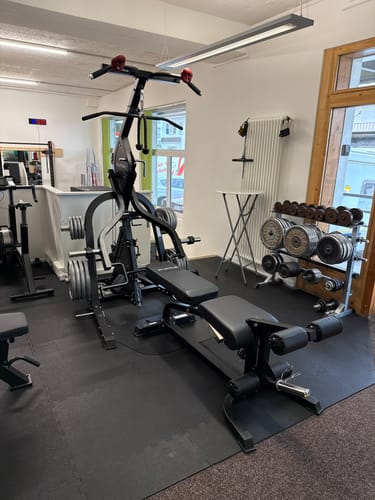 Die aufgebaute Triton Multigym Triplex Station eines Kunden, mit Hantelbank und Gewichten in einem Heimstudio.