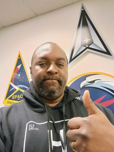 Reviewer gives a thumbs-up while wearing the black Blame Hydrogen - Unisex Hoodie.