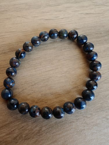 Photo d'un client montrant le bracelet en Piétersite. Les perles rondes ont de jolis reflets bleus et bruns.