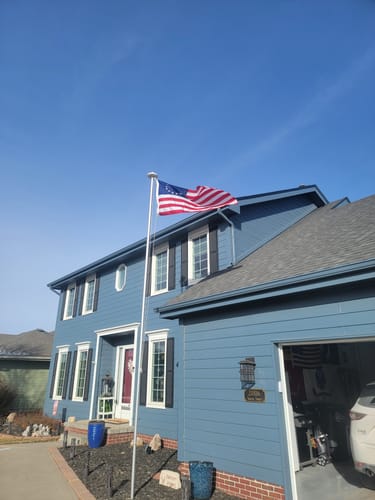 Reviewer's Betsy Ross flag flying on a flagpole in the front yard of their two-story blue house.