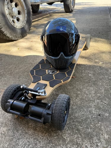 Customer's MEEPO ROVER electric skateboard with a black full-face helmet resting on the honeycomb-patterned deck.