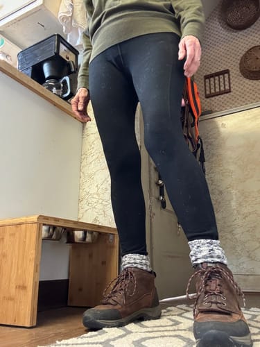 A customer wearing the black Piper Pocket Leggings indoors, paired with thick socks and hiking boots.