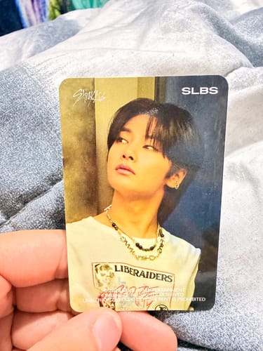 Customer's hand holding their Stray Kids mystery random photocard featuring the member I.N.