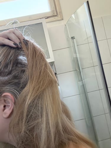 Reviewer holding up their darker blonde hair before using the Sunkissed Starter Kit.