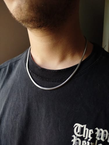 Primer plano de un cliente luciendo la Cadena Viper 4mm plateada en su cuello sobre una camiseta negra.