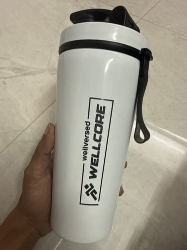 Customer holding the white Wellcore steel shaker with a black lid and logo.