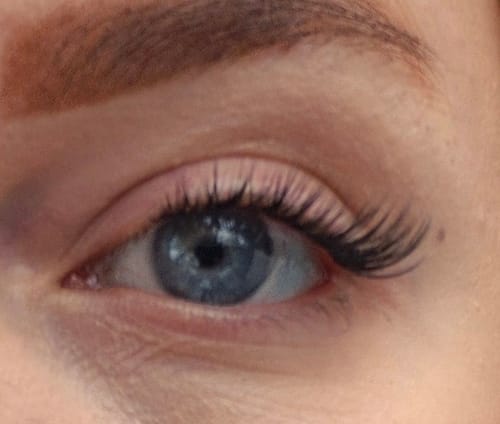 Nahaufnahme des blauen Auges einer Kundin mit den langen Wimpernextensions PRETTY WOMEN MAXI für einen Cat-Eye-Look.
