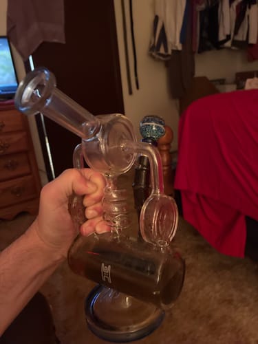 A customer holds their Condenser Glass Percolator Bong, which contains water from use.