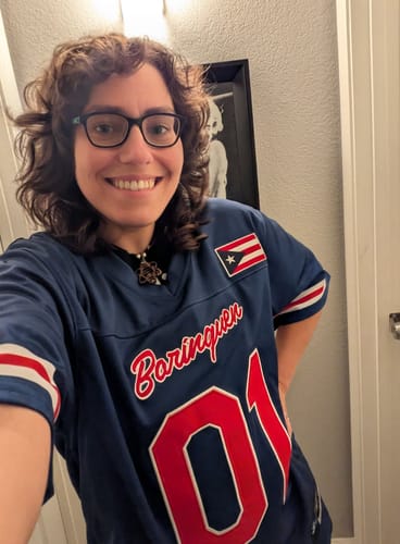 Reviewer smiling in their blue Puerto Rico Heritage Custom Football Jersey, showing the 'Borinquen' text and number '01'.