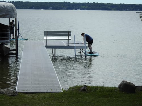 Reviewer's photo showing a person getting onto a paddleboard from a dock on a lake.