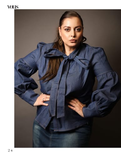 Reviewer posing in the denim blouse with puff sleeves and a large bow at the high neck.