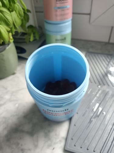 Customer's open blue jar of Original Hormone Gummies, showing a few dark gummies left inside on a counter.
