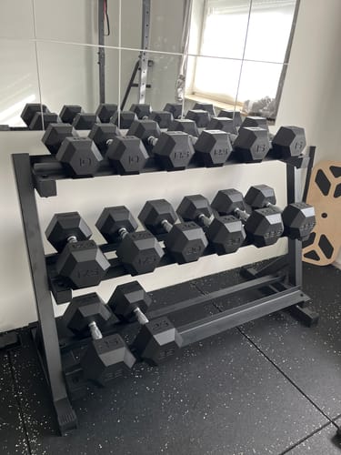 Das Hexagon PRO SET Cerberus eines Kunden, ordentlich auf dem schwarzen Hantel-Rack in einem Home-Gym platziert.